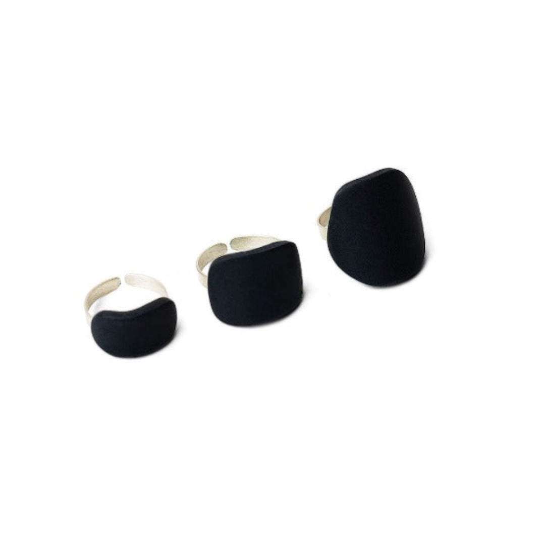 A set of three black polymeric clay rings with sterling silver 925 accents, displayed against a white background.
