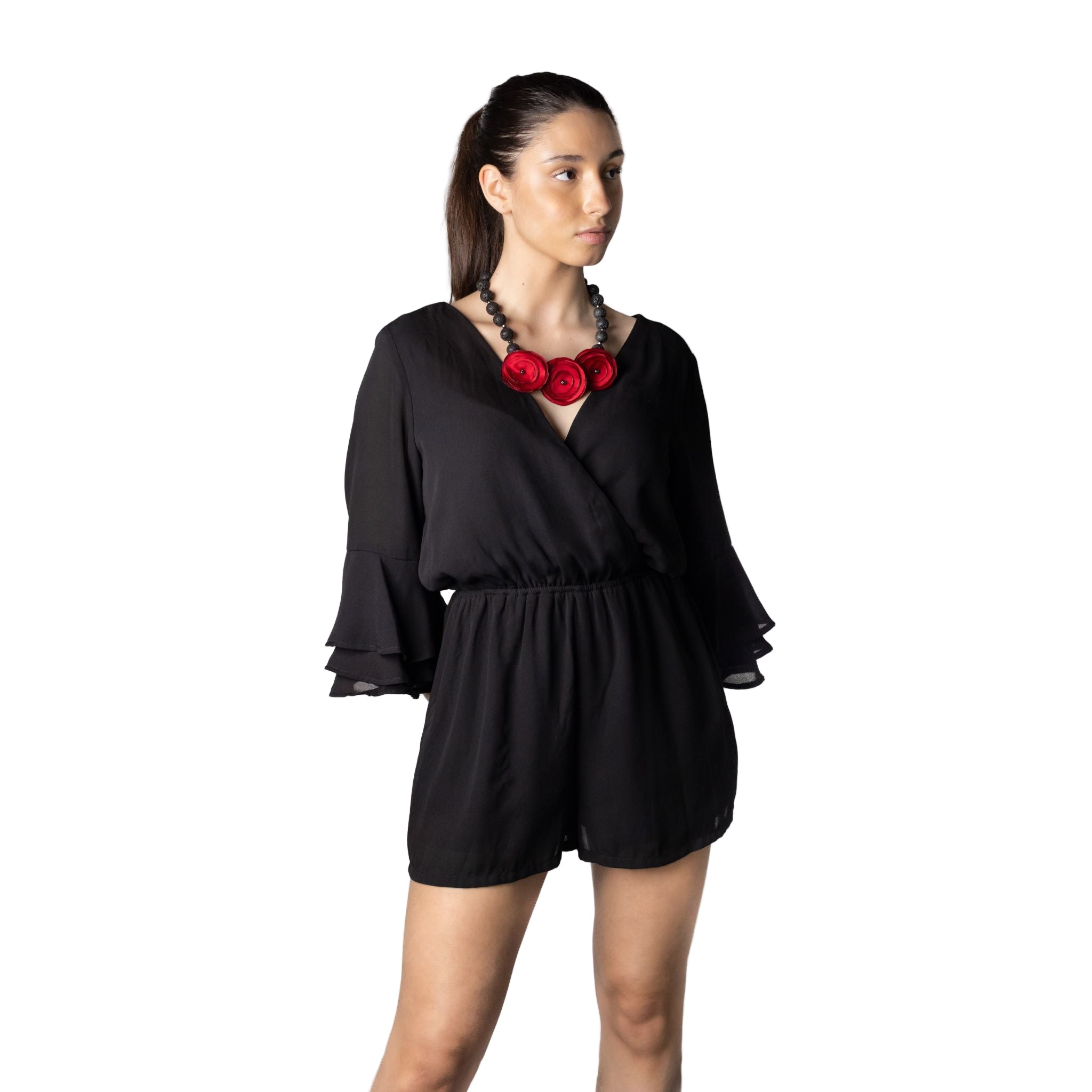 Woman wearing a black romper with red floral accessories on a white background