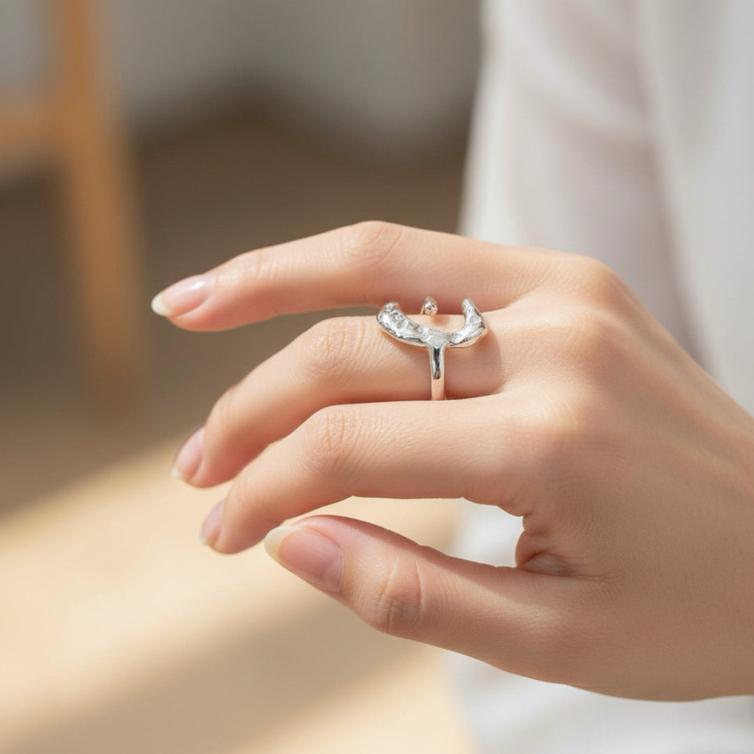 Hand wearing a silver ring with a blurred background