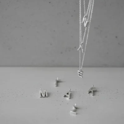 Silver necklace and earrings on a gray surface