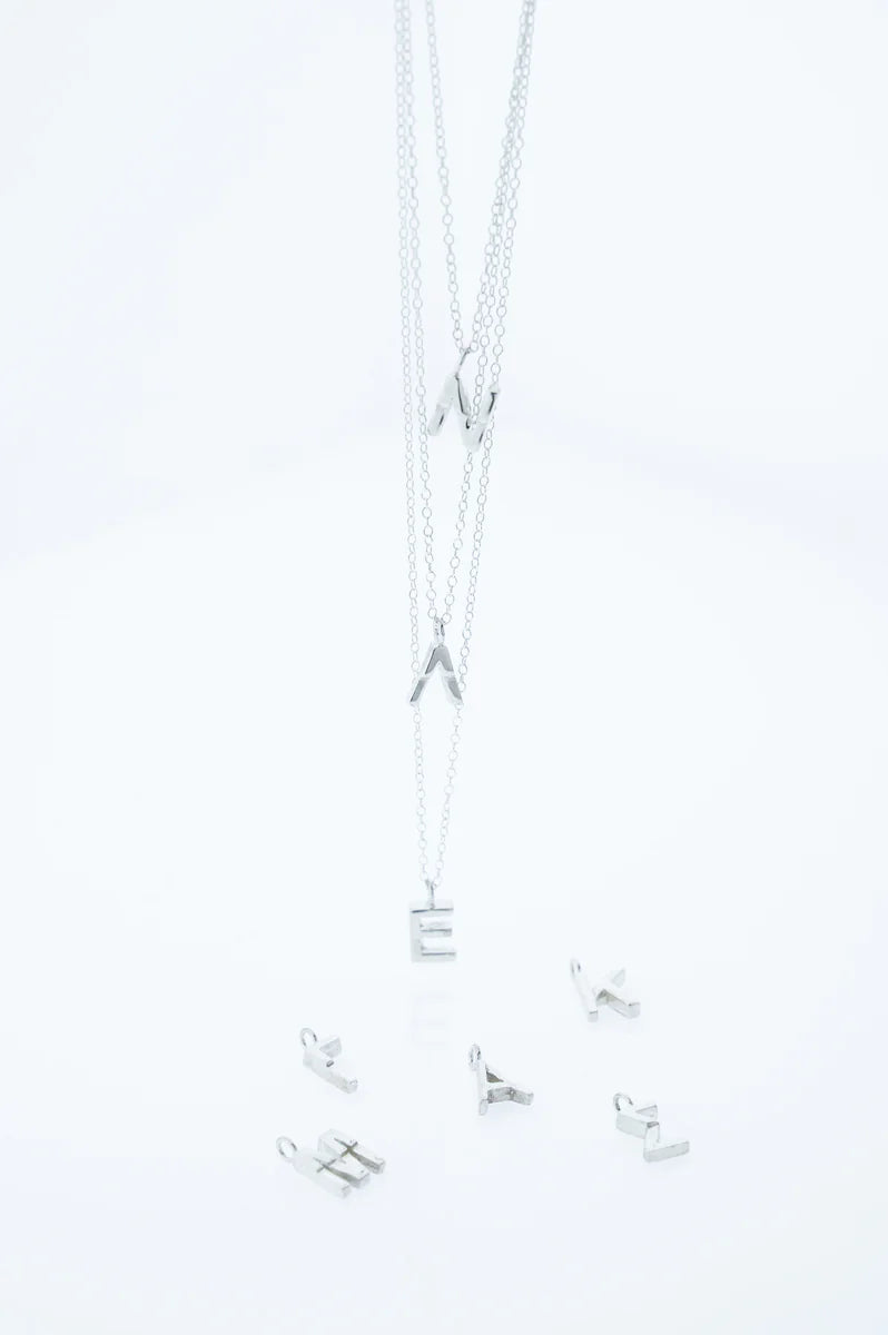 Silver necklace with letter pendants on a light gray background