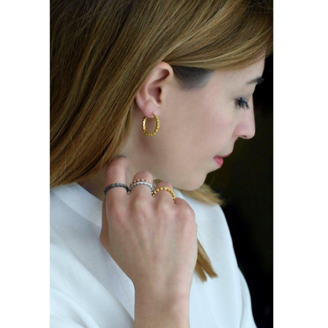 A gold-plated adjustable ring with a textured band, viewed from a side angle against a white background.