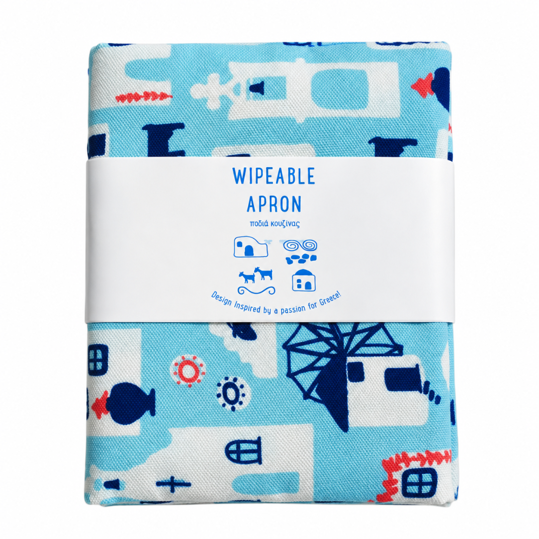 A folded fabric apron with a light blue and white patterned design featuring whimsical illustrations, wrapped in a white paper band that reads 'WIPEABLE APRON'.