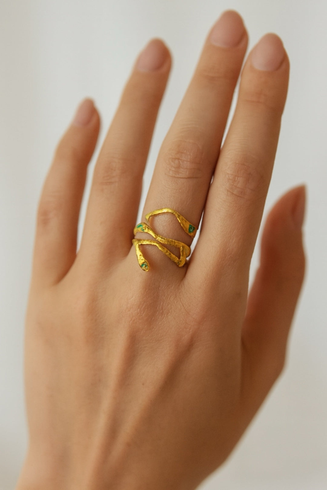 Gold ring on a person's finger against a neutral background