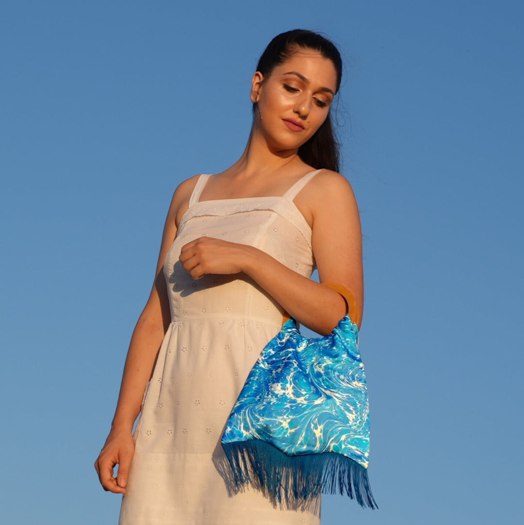 Woman holding a blue handbag against a clear blue sky