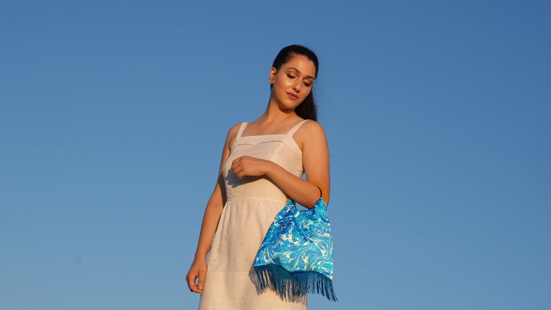 Woman holding a blue floral handbag against a clear blue sky