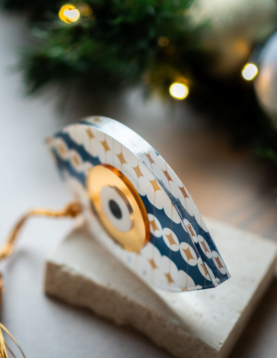 Decorative item with floral pattern on a stand, blurred Christmas tree in the background
