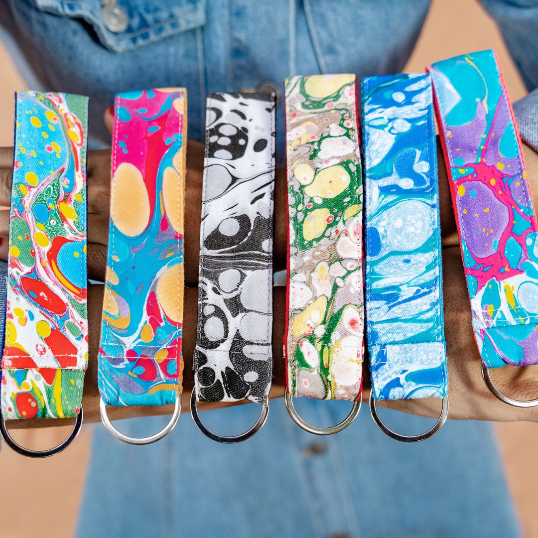 Colorful keychains held by a person wearing blue jeans.