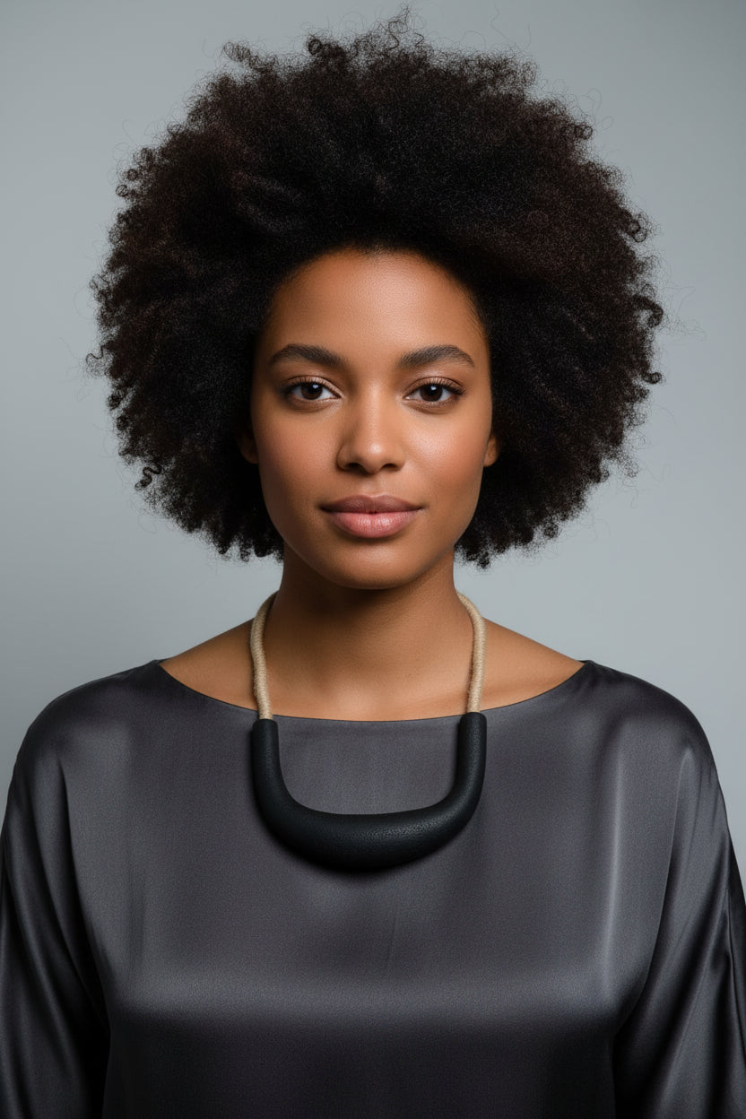 Woman wearing a white blouse with a black necklace against a gray background