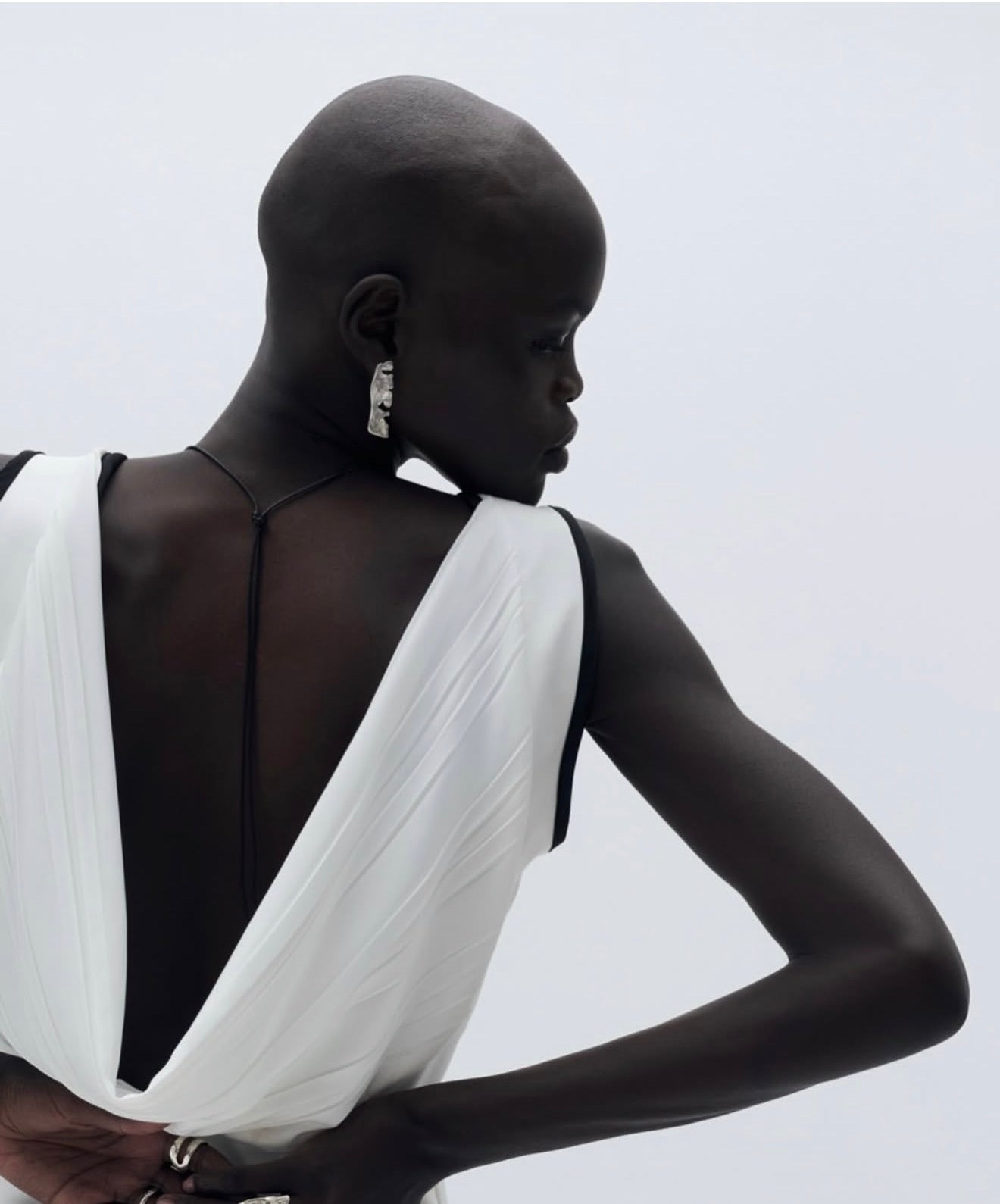 Woman wearing a white dress with a black back against a light gray background