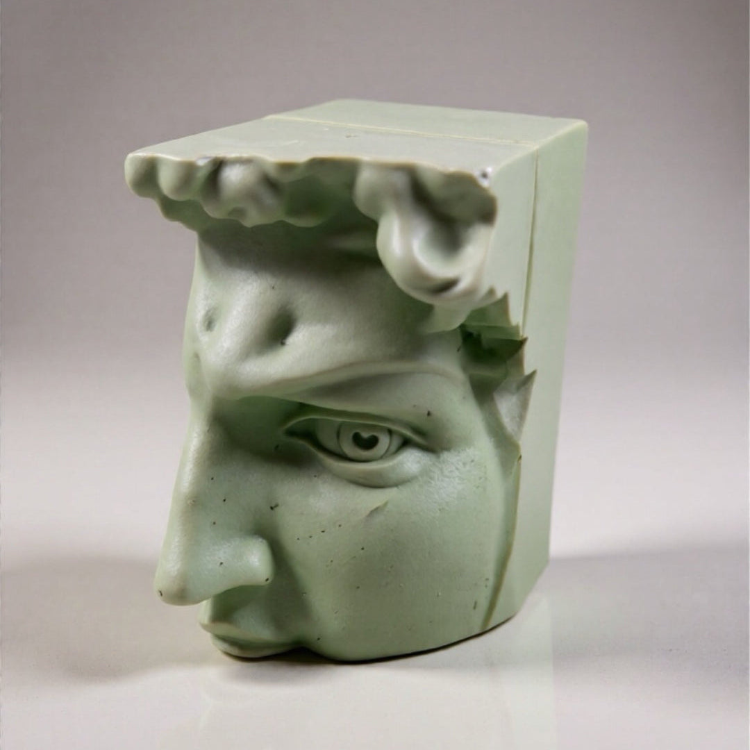 Green ceramic sculpture of a face with outstretched hands on a gray background