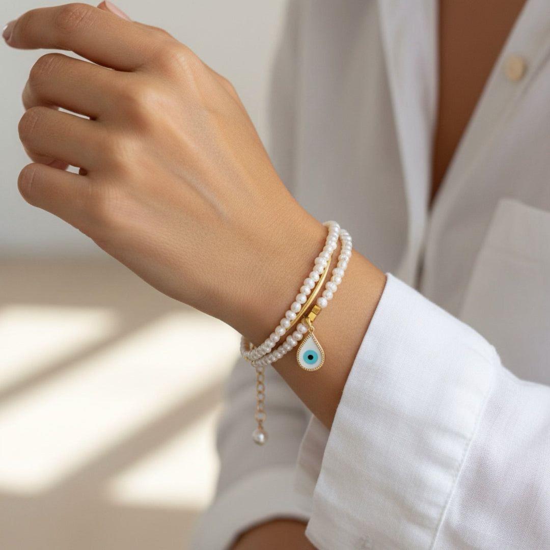 Hand wearing multiple bracelets with a neutral background