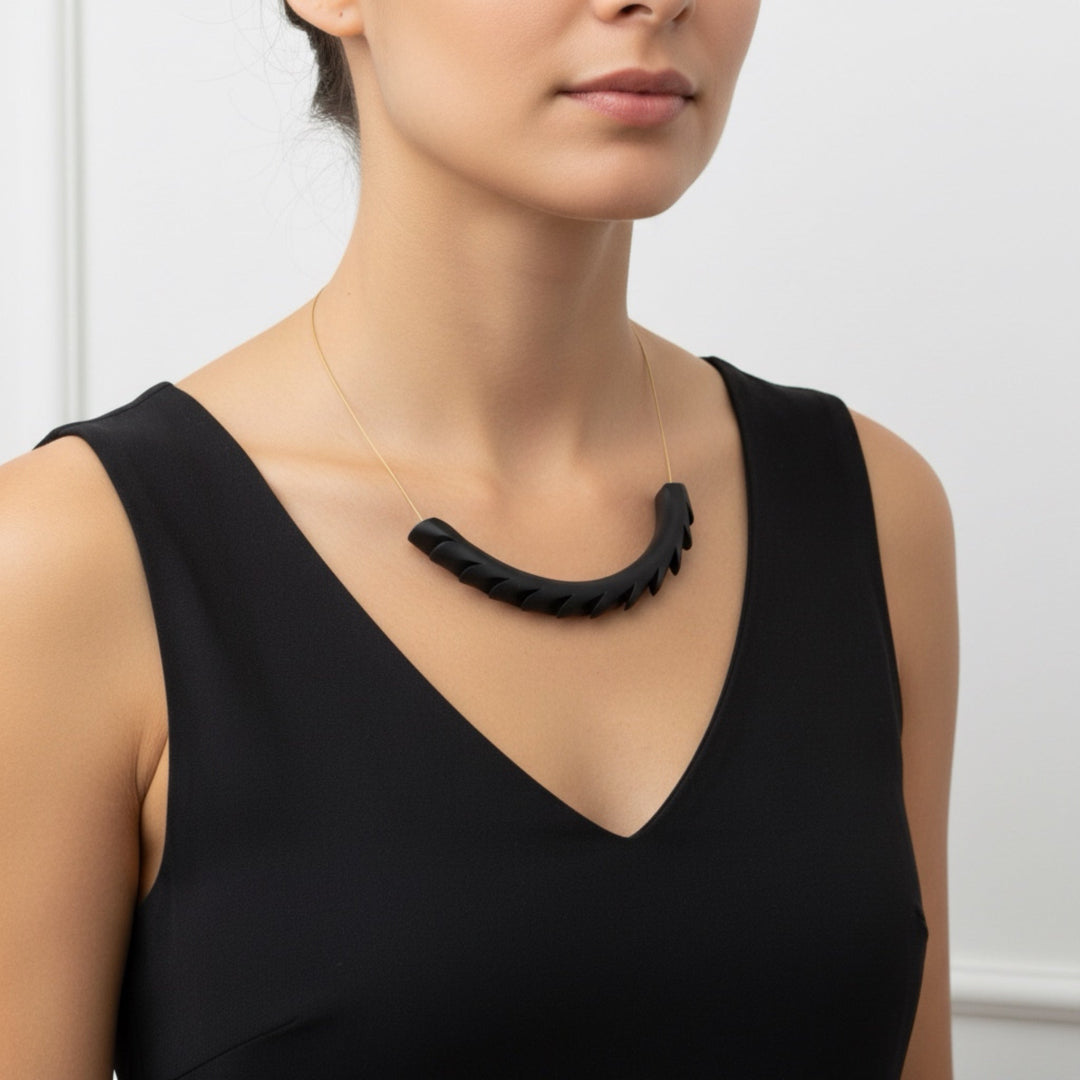 Woman wearing a black necklace against a plain background