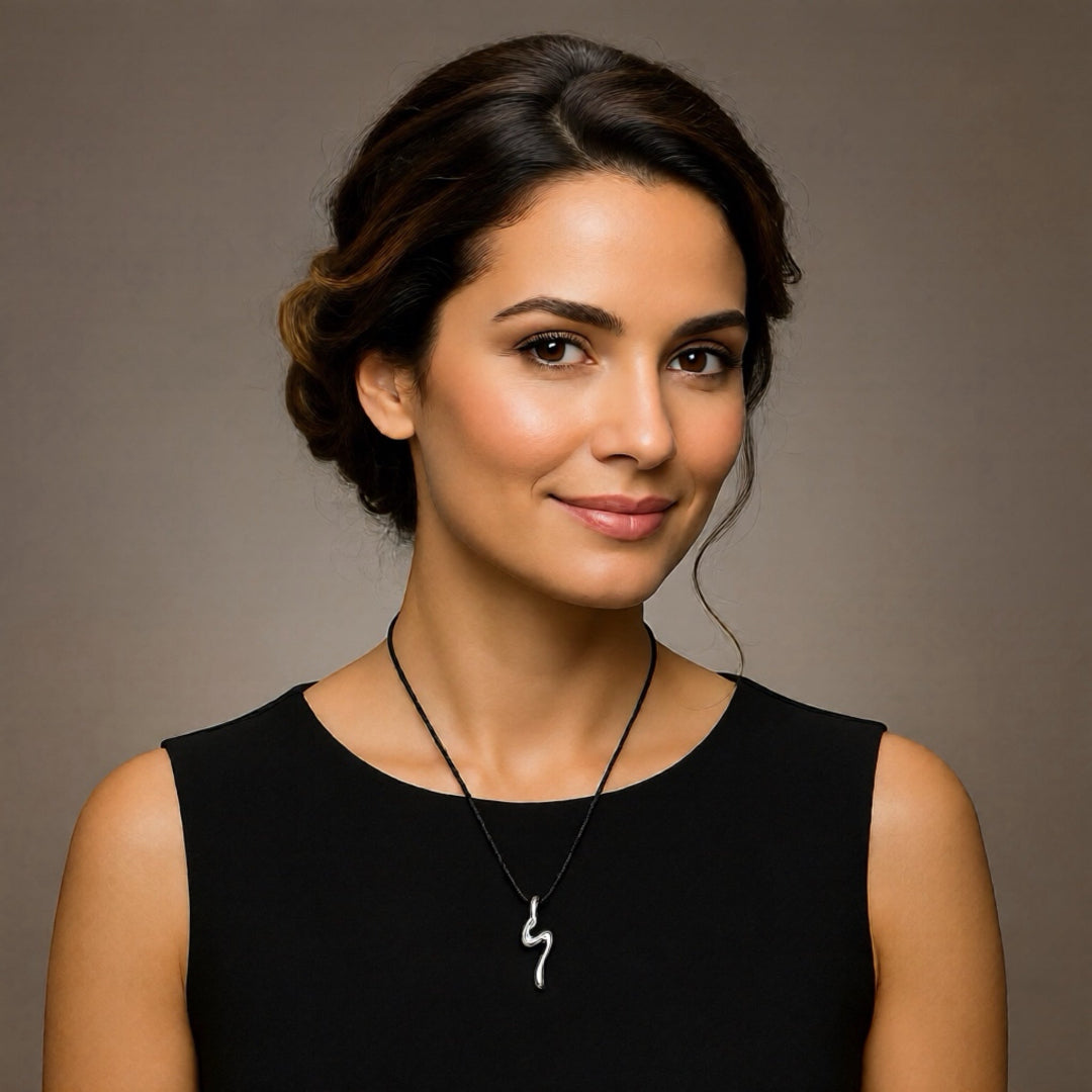 Woman wearing a black sleeveless top and a necklace with a unique pendant against a neutral background