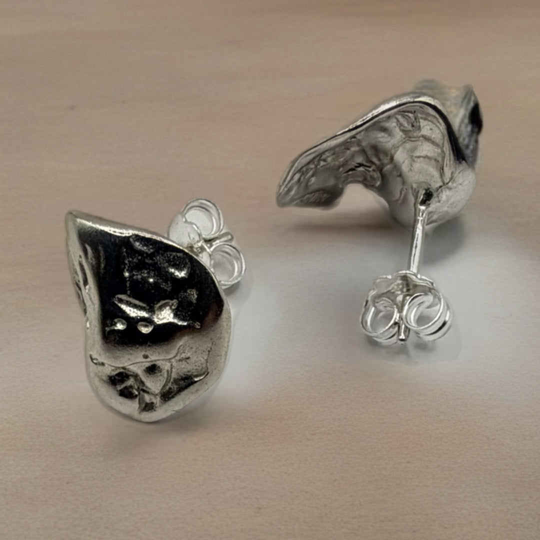 Pair of silver earrings on a beige surface