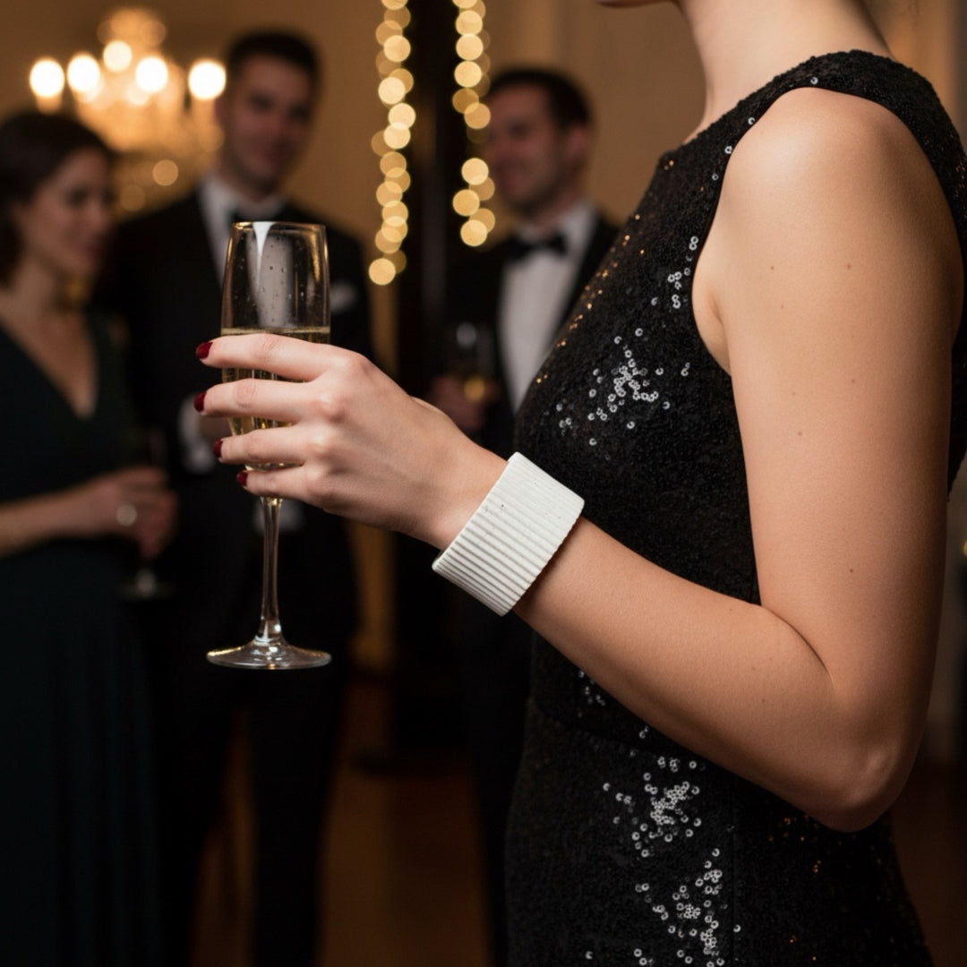 Person in a black sequined dress holding a glass of champagne at a formal event.
