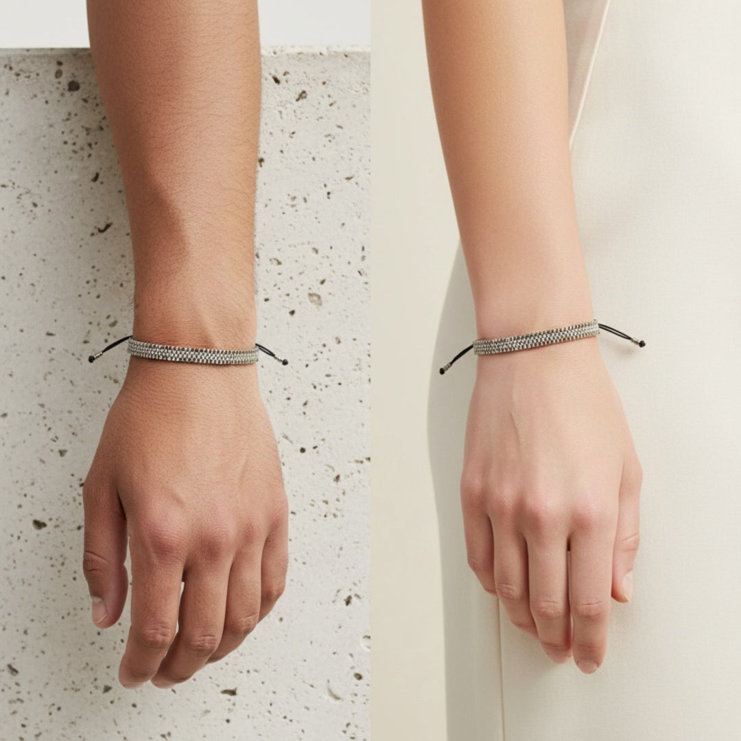 Two hands wearing thin bracelets on a light background