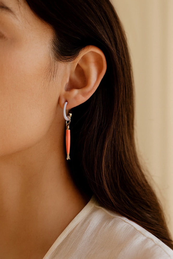 Close-up of a person wearing an earring with a pink accent against a neutral background
