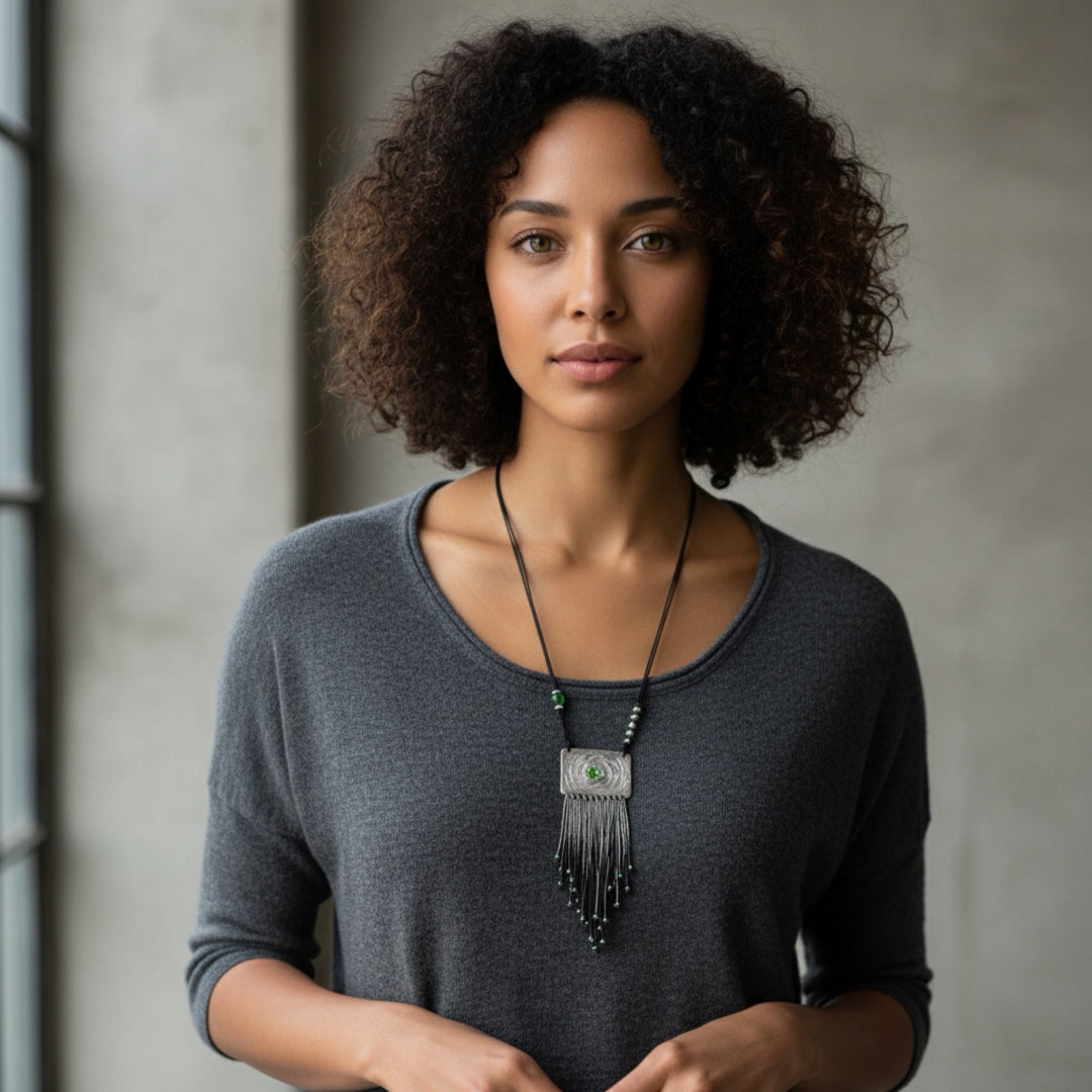Woman wearing a gray shirt and a necklace with a pendant against a neutral background