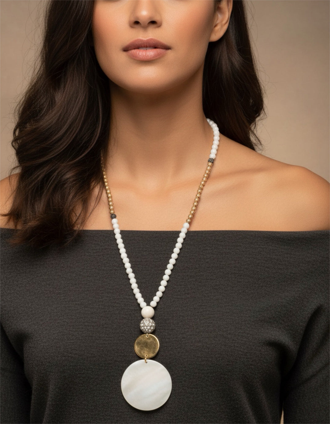 Woman wearing a long beaded necklace with a large pendant against a neutral background