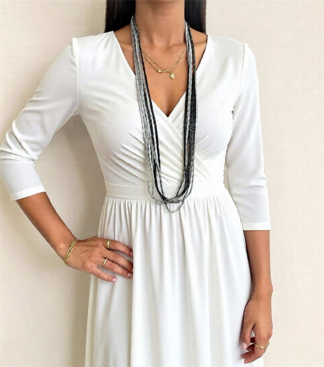 Woman wearing a white dress with long sleeves against a plain background