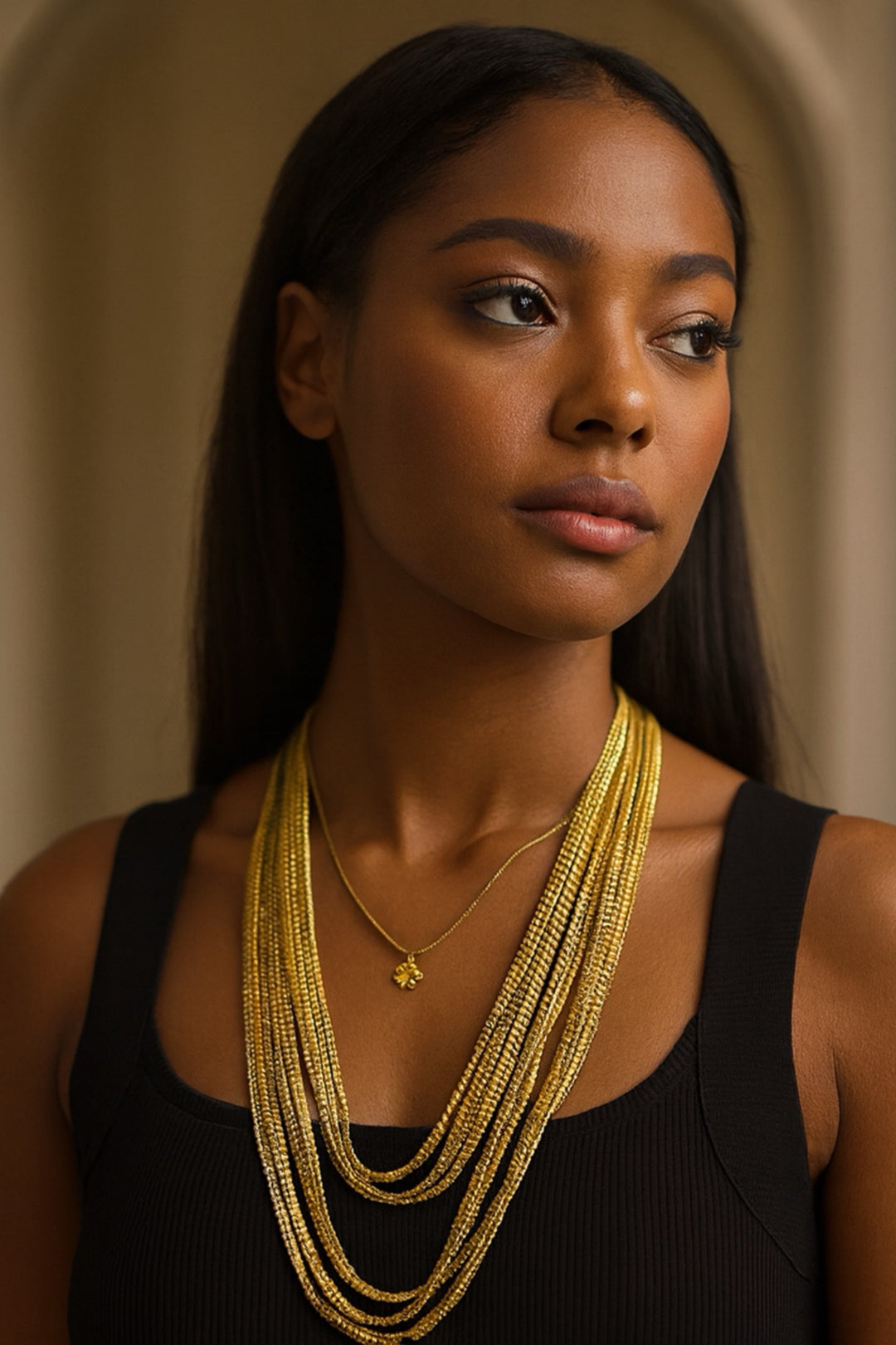 Woman wearing multiple gold necklaces against a neutral background