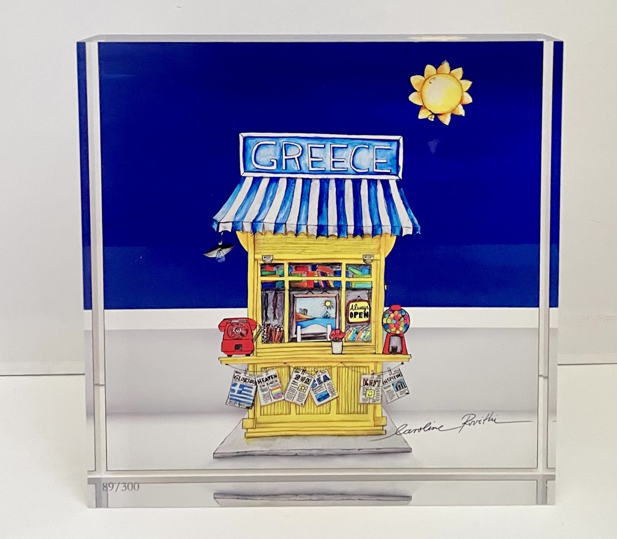 A plexiglass plaque featuring a colorful illustration of a Greek kiosk with a blue sky and sun motif in the background.