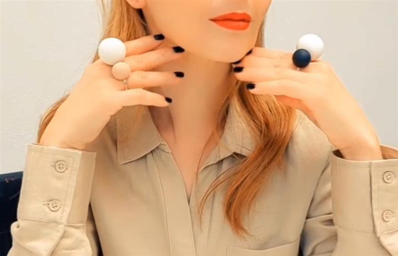 Woman wearing large round earrings with a neutral background