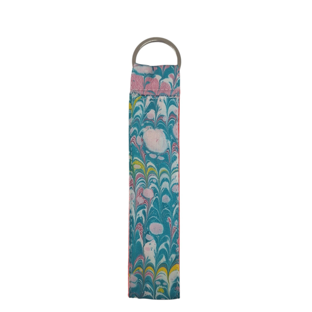 Floral-patterned fabric roll with a metal ring on a white background