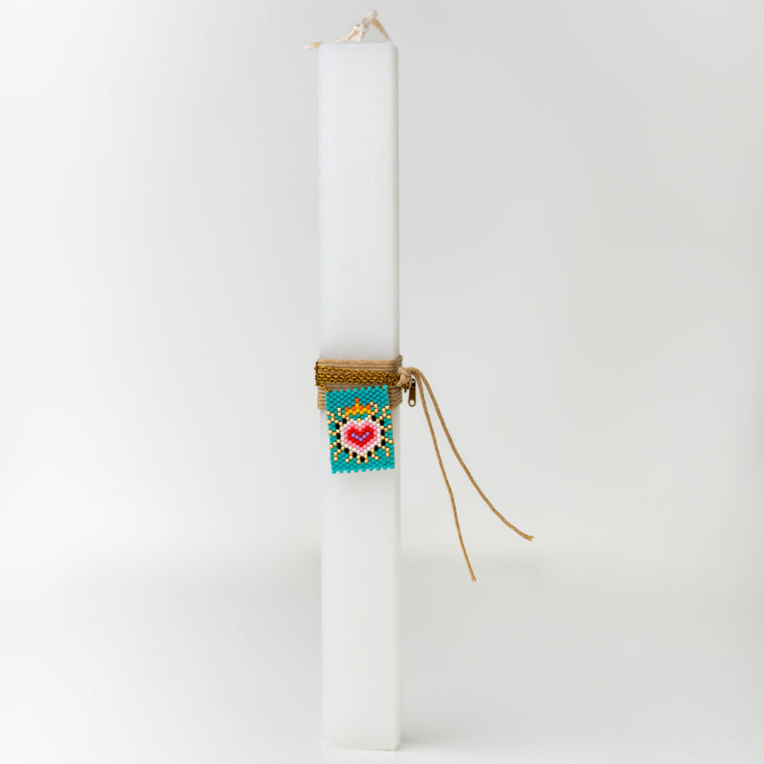 White candle with decorative box and ribbon on a white background