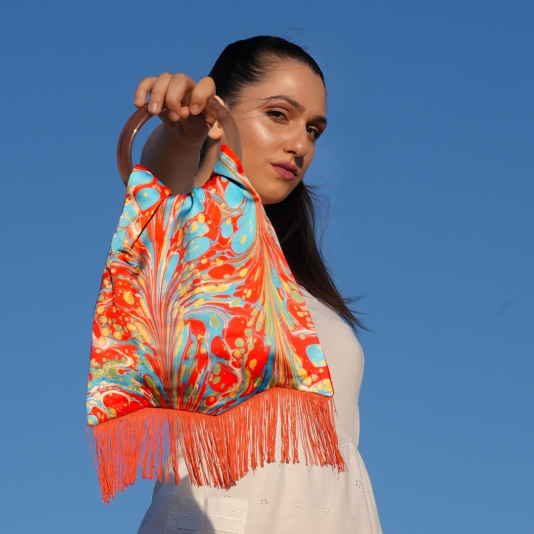 Woman holding a colorful scarf against a clear blue sky