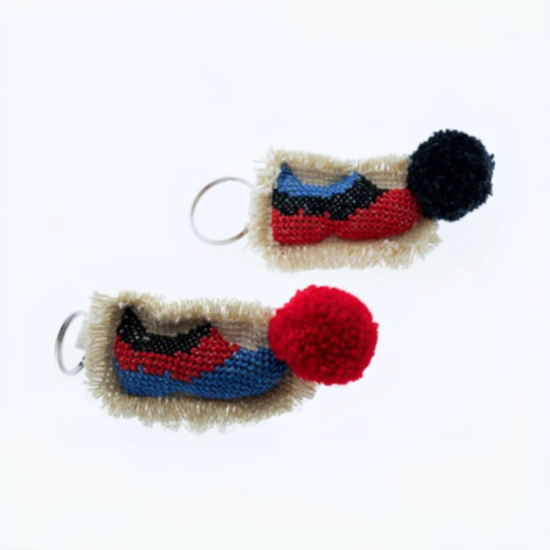 Two keychains with colorful designs and a pom-pom on a white background.