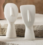 Two white ceramic face sculptures on a textured surface