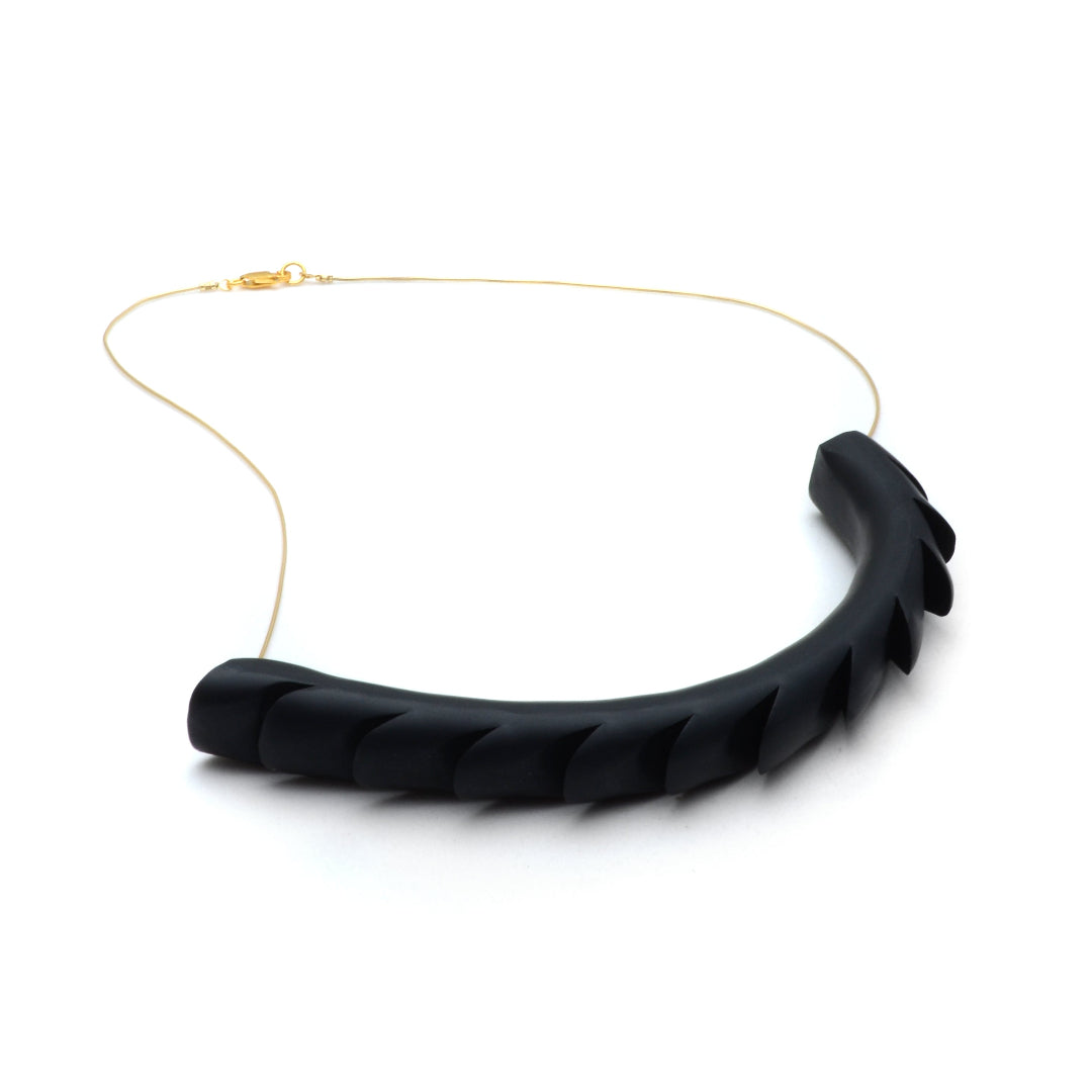Black ribbed necklace on a white background