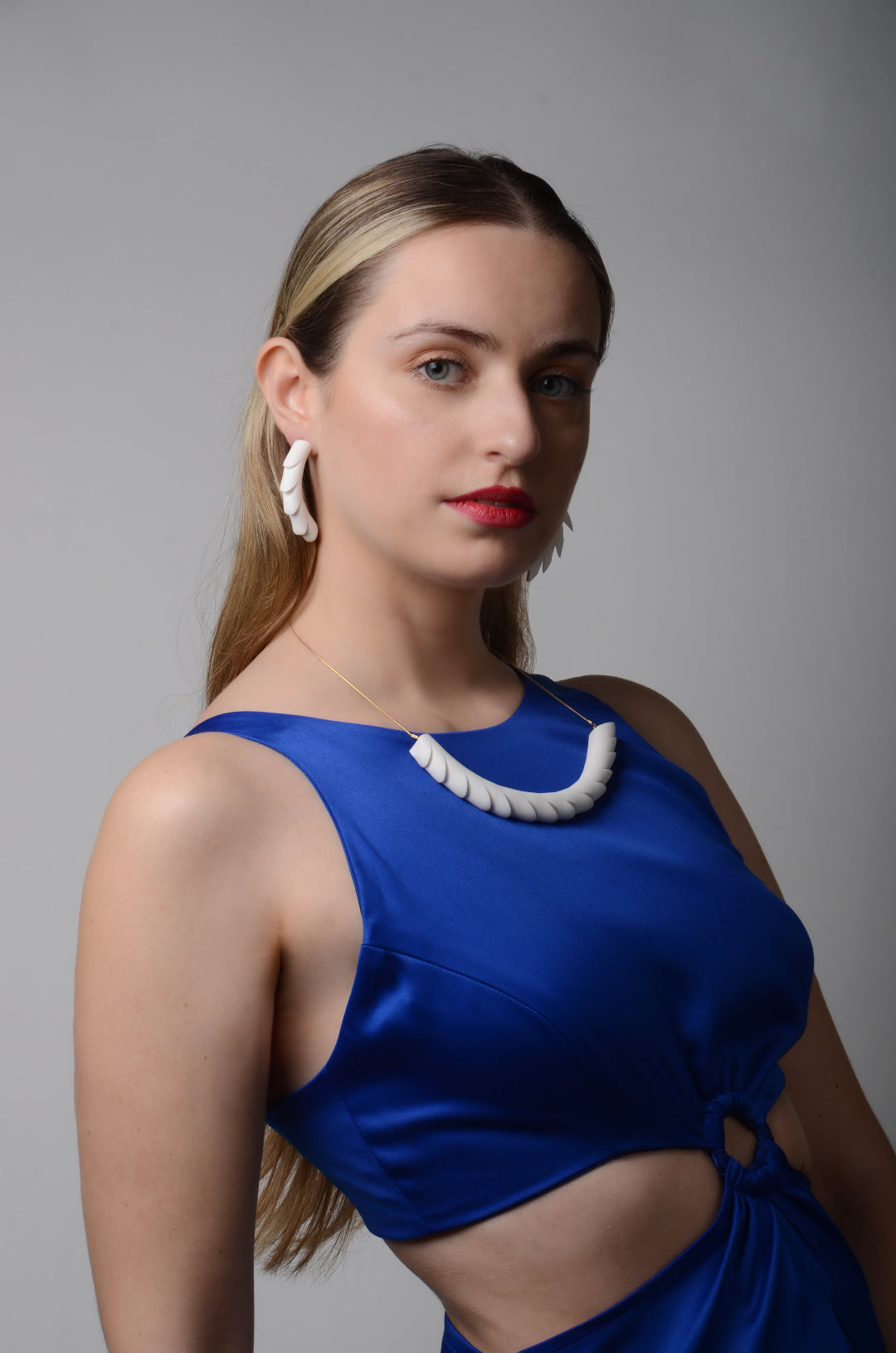 Woman wearing a blue dress with cut-out design against a gray background