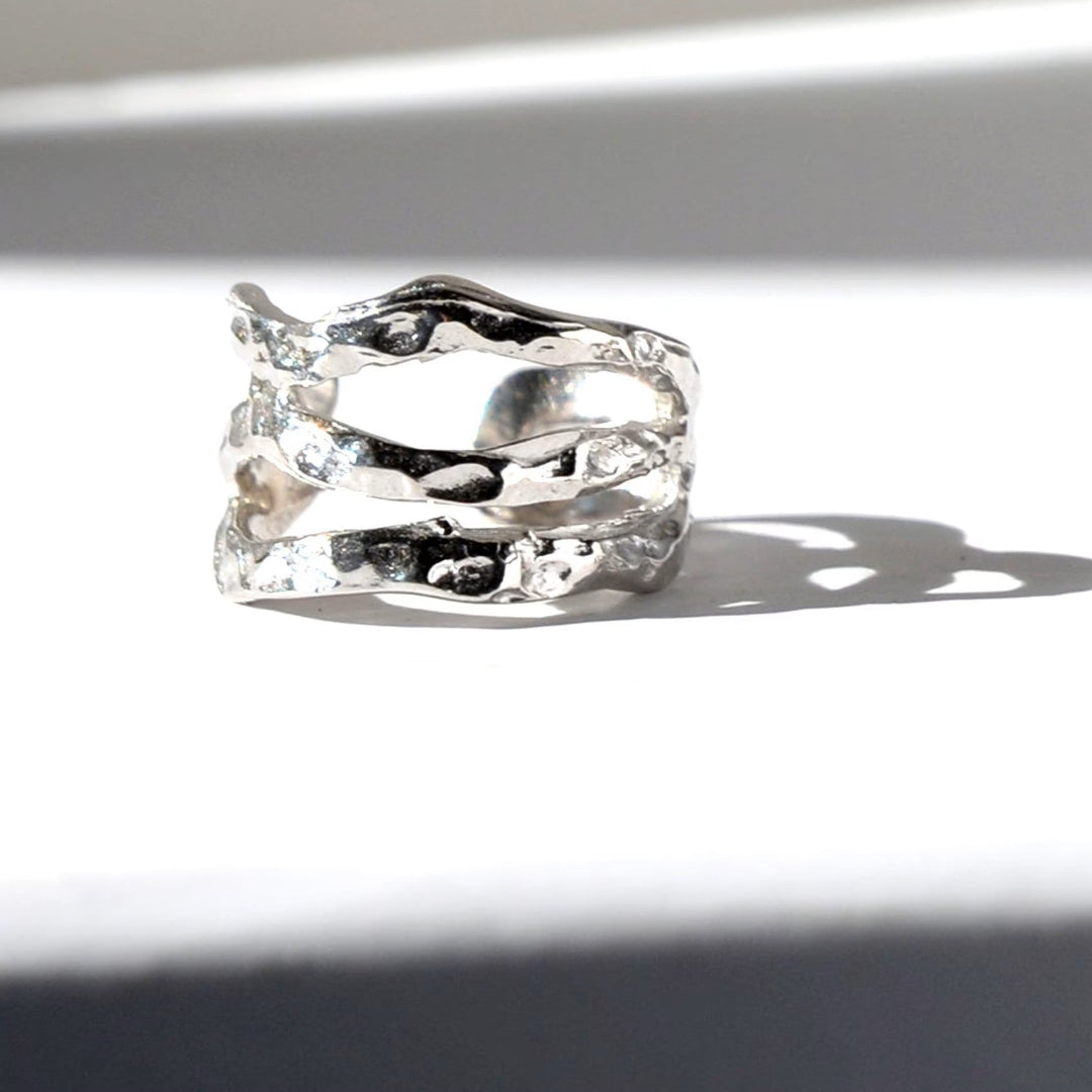 Silver ring with wavy design on a white background