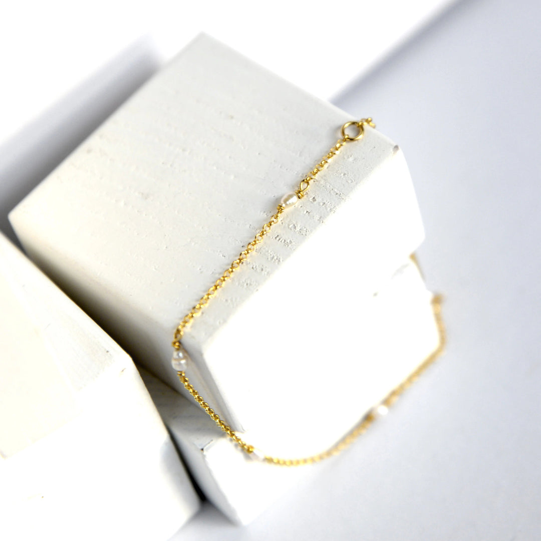 Gold bracelet on a white stone surface