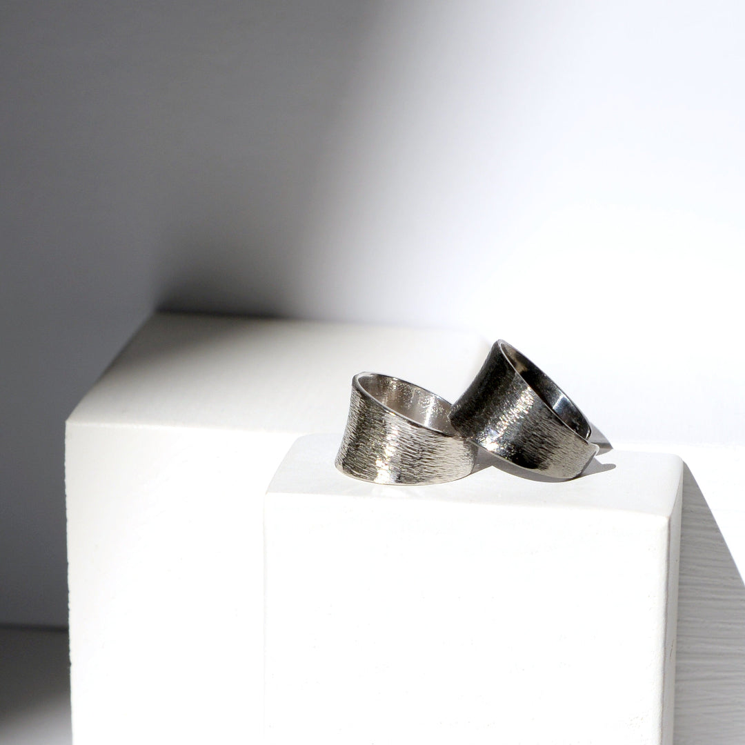 Silver ring on a white surface with a gray background