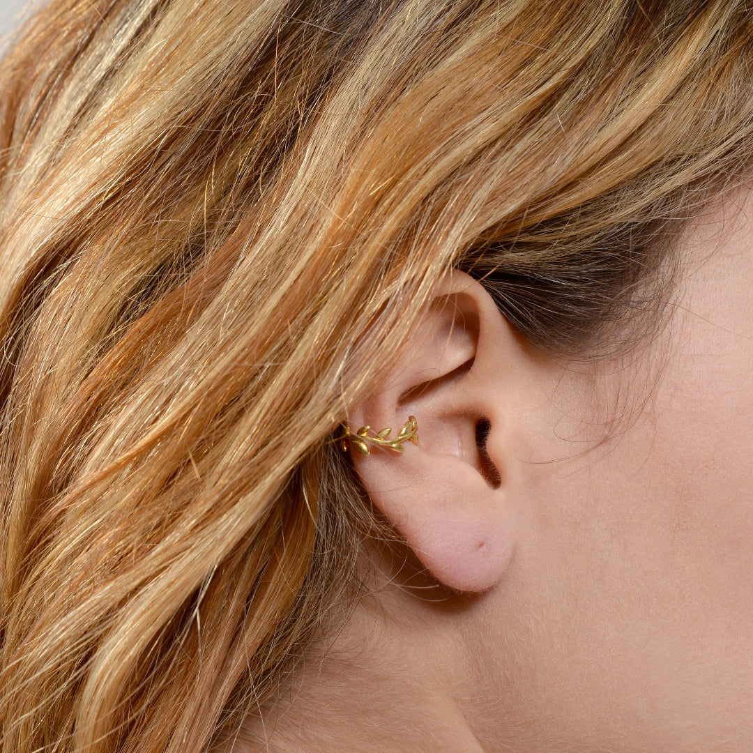Close-up of an ear with a gold earring and blonde hair.