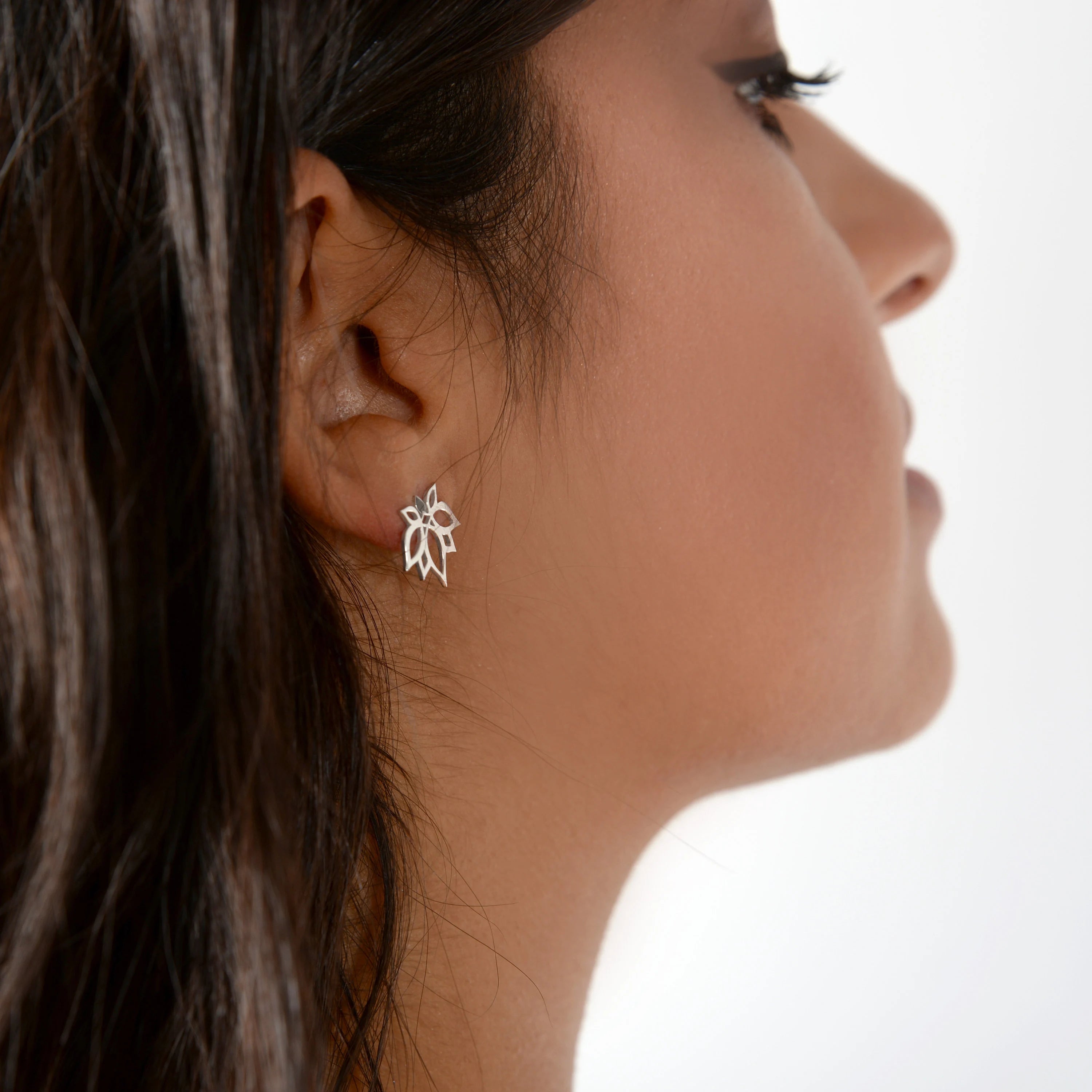 Close-up of a woman wearing a silver leaf-shaped earring on a white background
