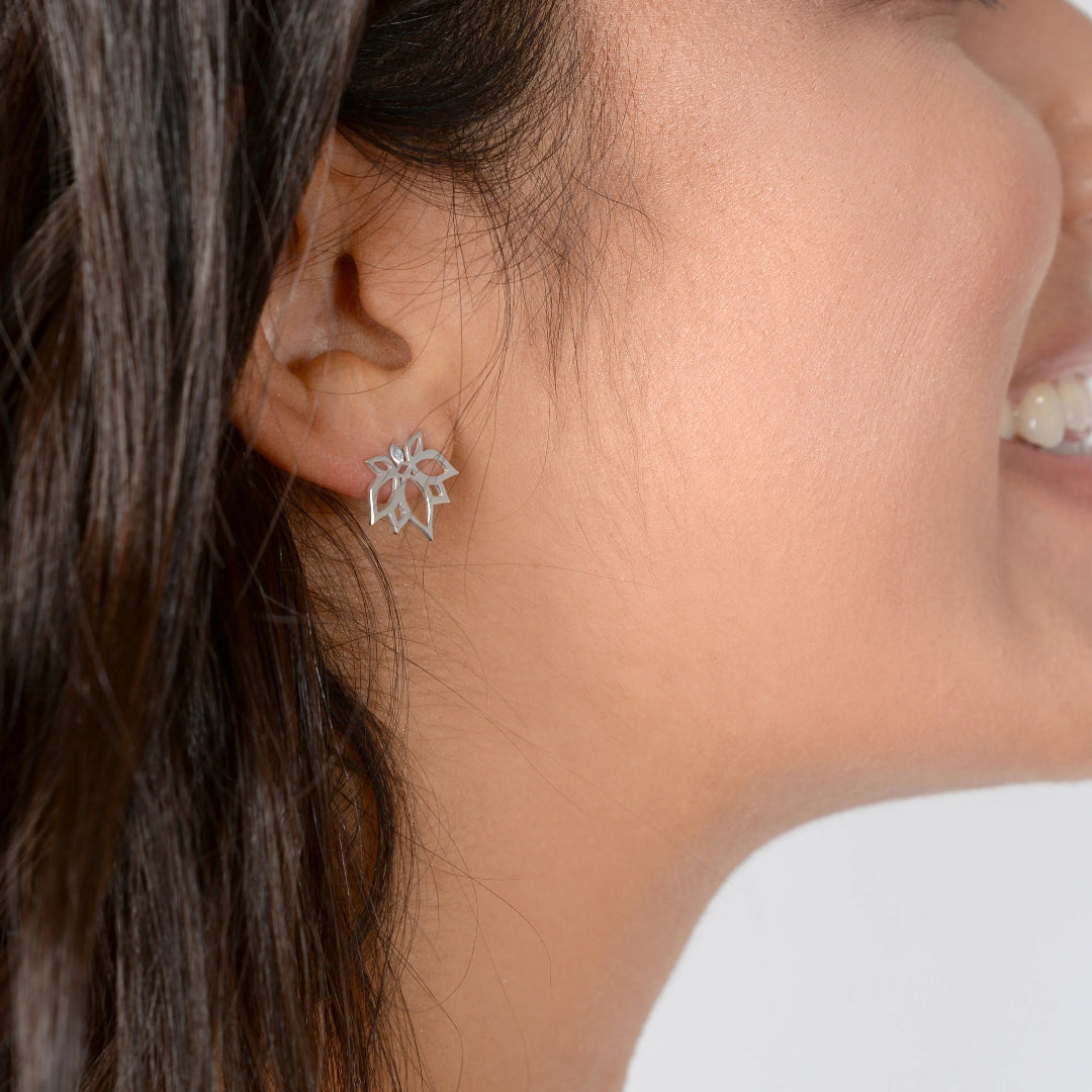 Close-up of a person wearing silver floral earrings.