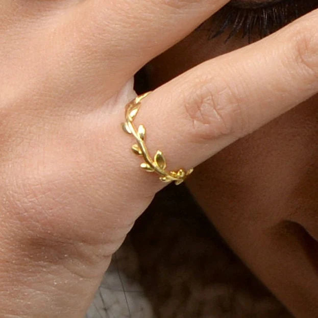 Gold ring with leaf design on a finger