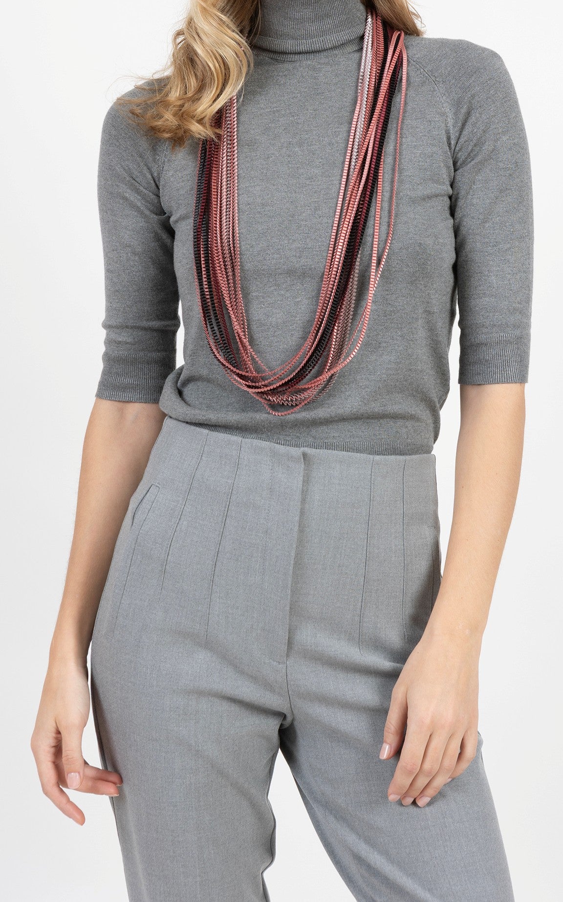 Person wearing a gray turtleneck and pants with a multicolored scarf.