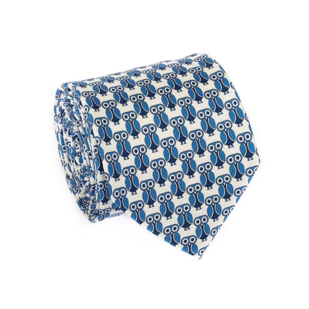 A rolled necktie featuring a repeating pattern of blue and navy owls with white eyes on a white background.