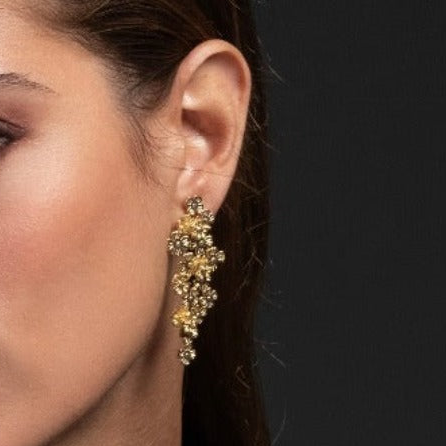 Close-up of a person wearing a gold earring against a dark background