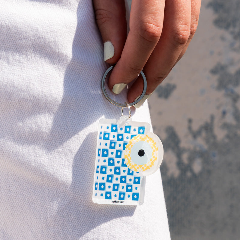 Keychain with blue geometric pattern held by a hand against a white background