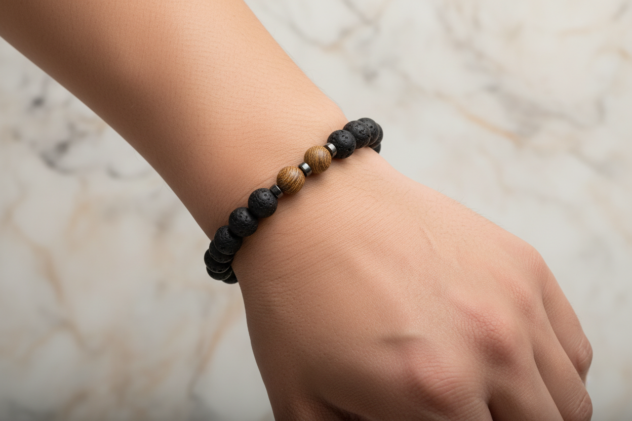 Bracelet with black and brown beads on a wrist against a marble background