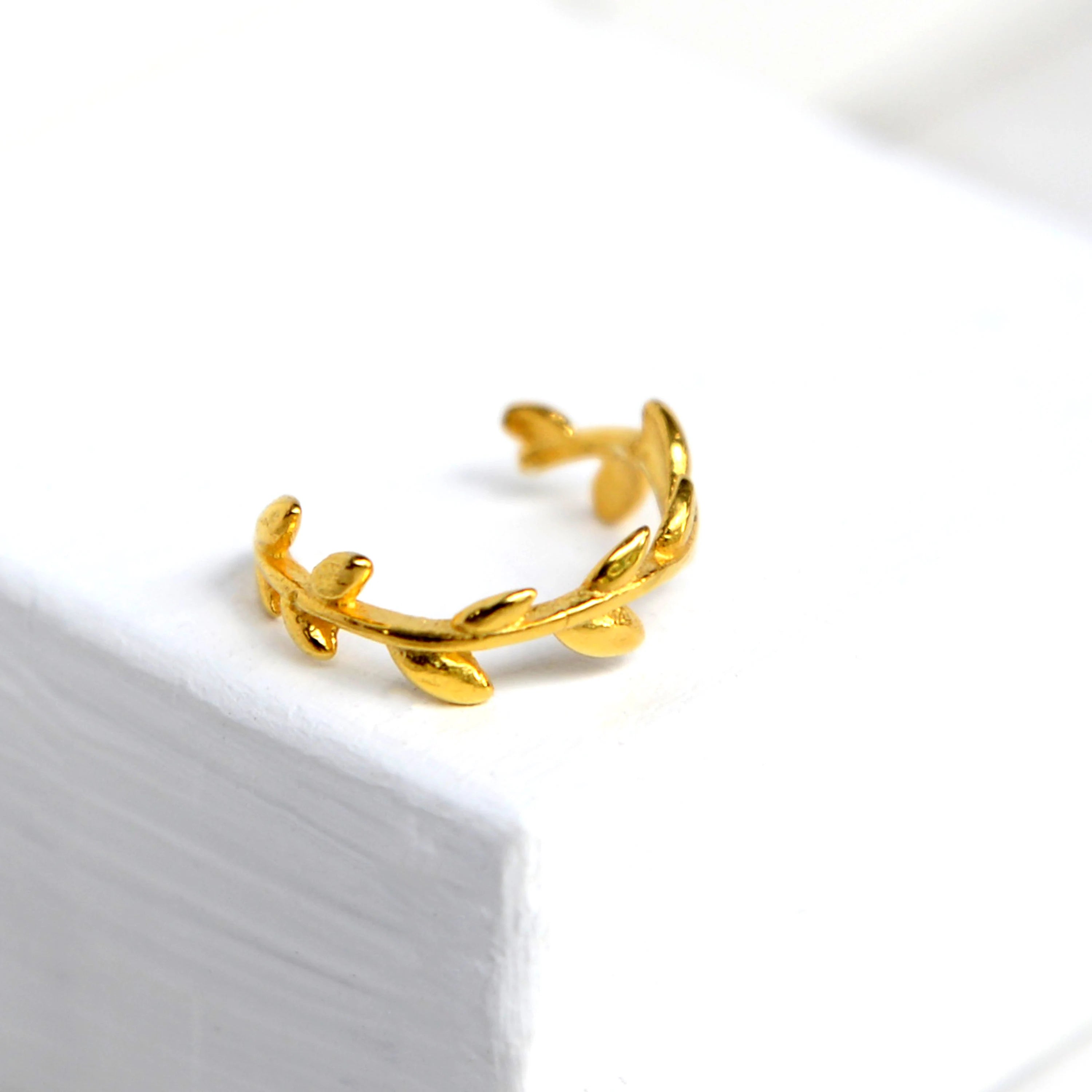 Gold leaf-shaped earring on a white background