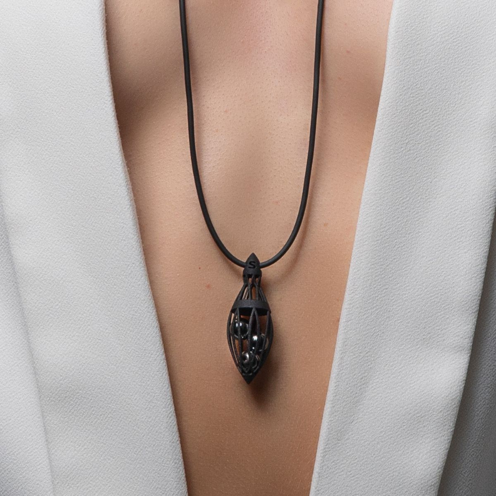Black pendant necklace on a person wearing a white garment