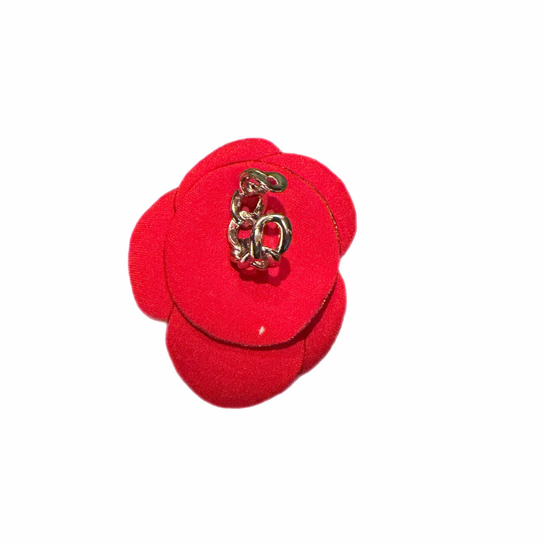 Red flower-shaped object with a gold charm on a white background